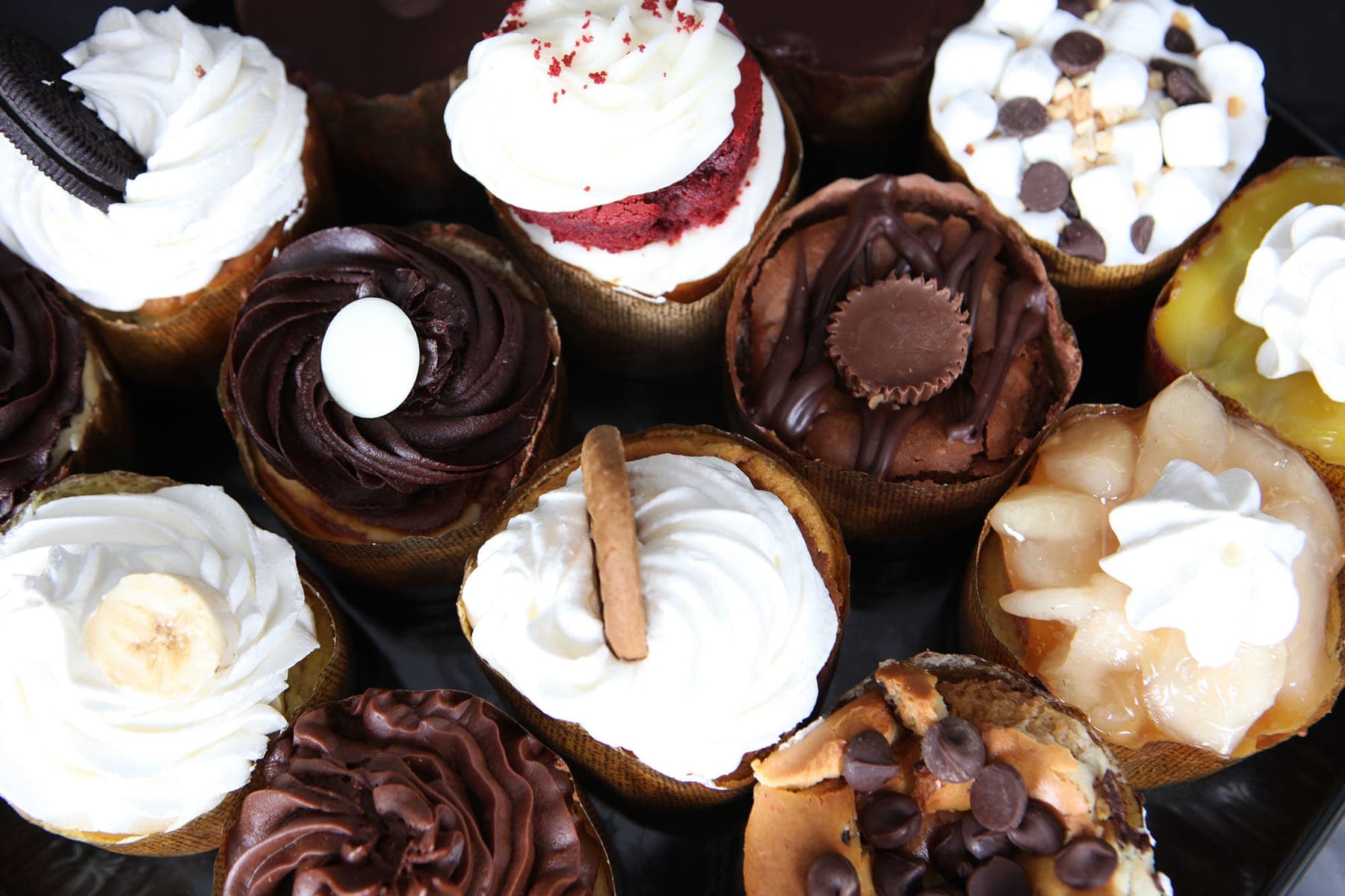 Assorted cheesecake cups topped with whipped cream, chocolate, marshmallows and fruit